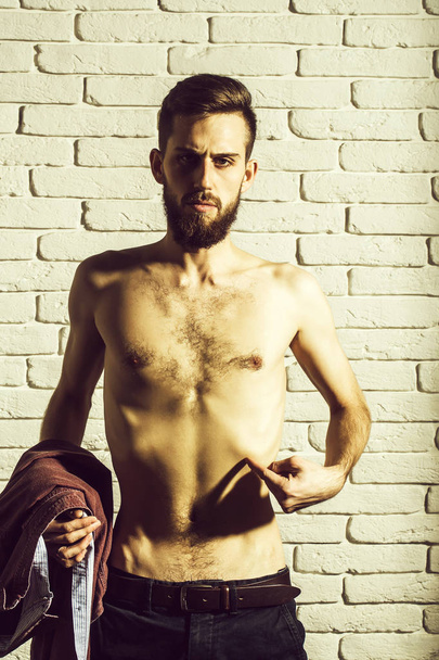 slim bearded man with thin bare torso on brick background - Фото, изображение