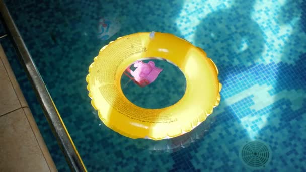 4 k video van gele opblaasbare ring en plastic speelgoed op wateroppervlak bij zwembad - Video