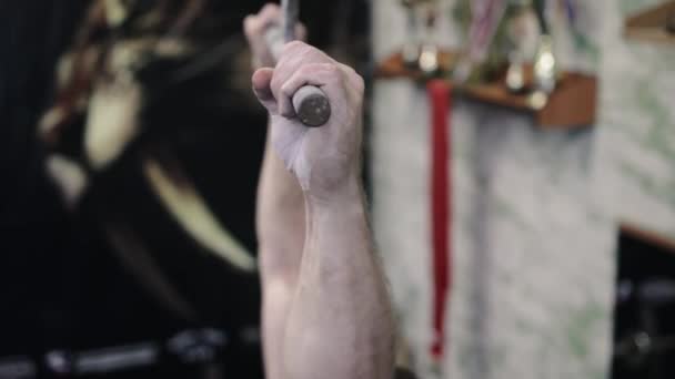 Tilt up of shirtless sportsman doing pull-ups on bars during cross-training workout at gym - Felvétel, videó