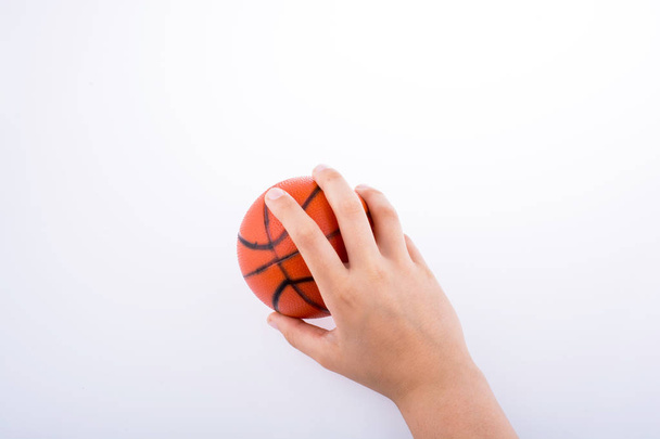 Hand holding an orange basketball model on a white background - Fotografie, Obrázek