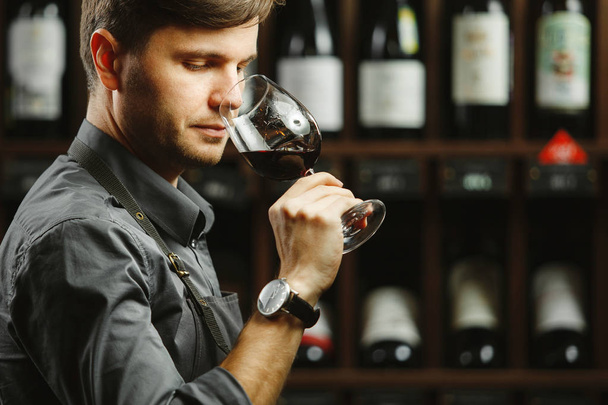 Bokal of red wine on background, male sommelier appreciating drink - Foto, imagen