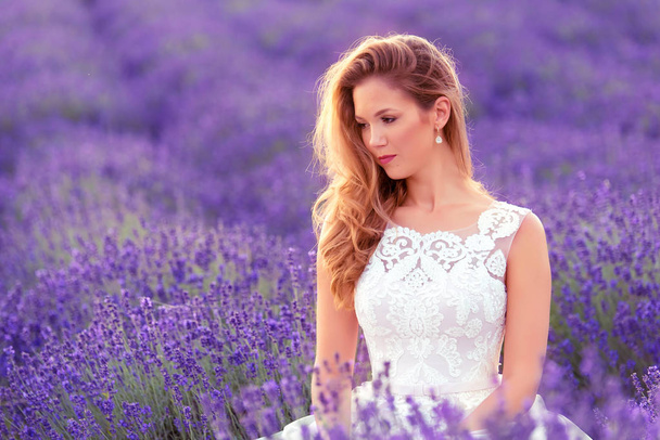 Beautiful bride in wedding day in lavender field. Beautiful blond woman - Fotó, kép