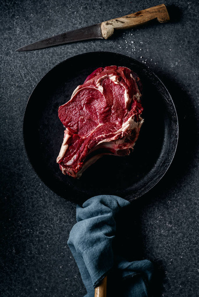 Top view of raw beef steak in pan on dark stone background - Foto, afbeelding