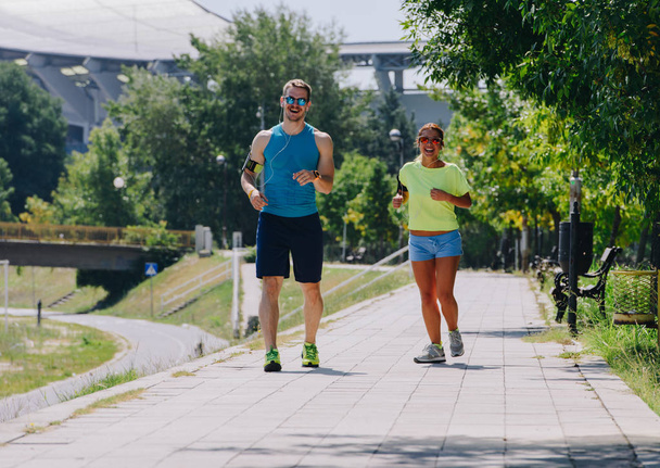 Two athletic people running through the riverside - Photo, Image