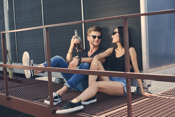 asian girlfriend and caucasian boyfriend with bottle of rum spending time together on roof - Foto, immagini