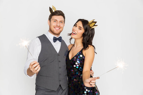 happy couple with crowns and sparklers at party - Фото, зображення
