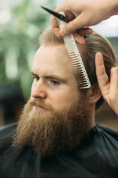 bärtiger Mann mit Haarschnitt und Haarschneidegerät - Foto, Bild