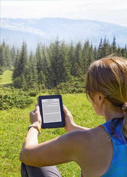 Закри жінка читання електронних книг в природі. Дівчинка тримає планшетний комп'ютер екран, який можна редагувати ізольовані на тлі лісу в Україні Драгобрат, Карпати, - Фото, зображення