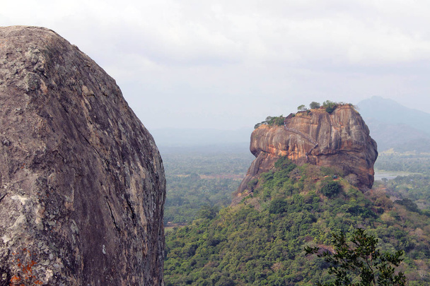 Rotsen en burcht op Sigiriya - The Lion Rock-, gezien vanaf Pidurangala Rock. Genomen in Sri Lanka, augustus 2018. - Foto, afbeelding