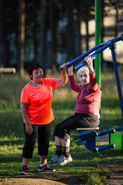 Літня жінка проводить вправи на спортивному майданчику в парку
. - Фото, зображення