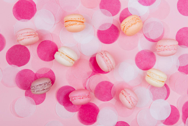 French macarons, confetti, and paper stars scattered on pink background, top view - Photo, Image