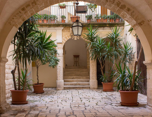 アーチ、鍋、階段およびランタンの植物と美しい裏庭。テラスの装飾。古代の中庭の背景。中世の建築物。居心地の良いイタリアの裏庭。旅行とアーキテクチャの概念. - 写真・画像