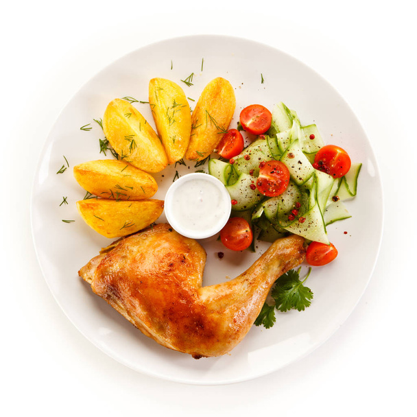 Top view of baked chicken leg with potato quarters, salad and mayonnaise on white plate - Foto, Bild