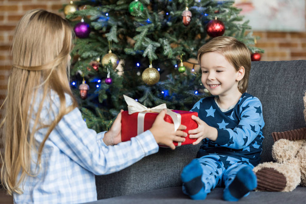 adorable happy children in pajamas holding christmas gift at home  - Foto, Imagem
