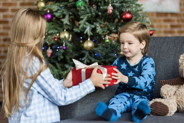adorable children in pajamas holding christmas gift at home  - 写真・画像