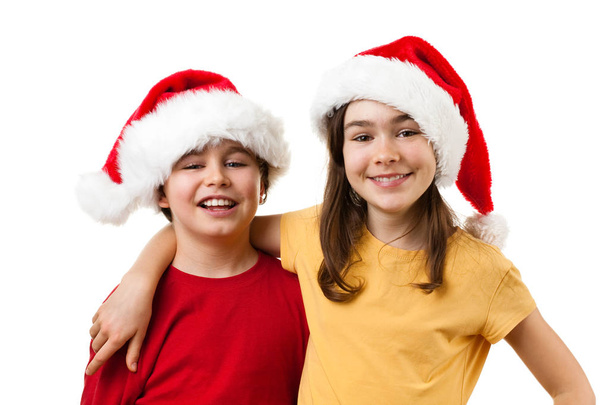 jongen en meisje in santa's hoeden - Foto, afbeelding