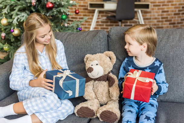 enfants heureux en pyjama tenant des cadeaux de Noël et regardant ours en peluche
 - Photo, image