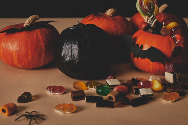тыквы, вкусные конфеты с желе и бумажные летучие мыши на столе, концепция Хэллоуина
 - Фото, изображение