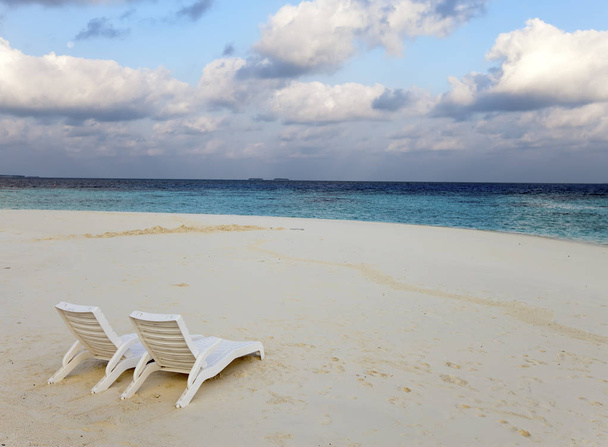 Beach lounge chairs on a beautiful tropical sand beach with cloudy blue sky. Maldives - Φωτογραφία, εικόνα