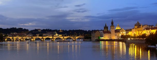 ヴルタヴァ川に架かるチャールズ Bridge(Karluv Most) プラハの美しい夜軽いパノラマの景観  - 写真・画像