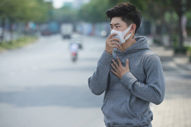 Young Vietnamese man having lungs problems, air pollution - Zdjęcie, obraz
