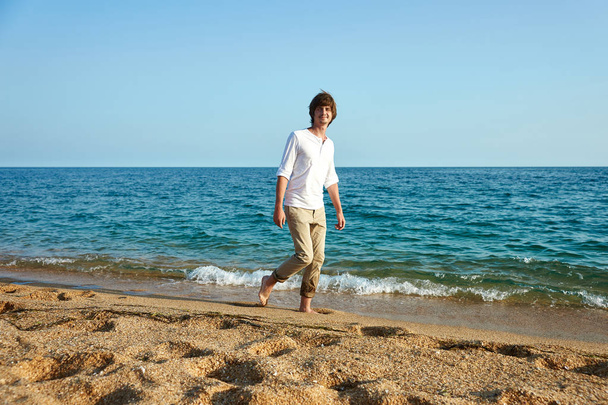 Handsome young man having fun on the beach by the sea - Fotó, kép