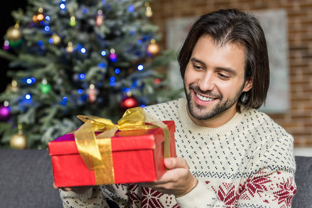 handsome happy man holding christmas present at home - Valokuva, kuva