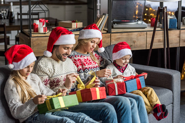 happy family in santa hats opening christmas presents and sitting together at home   - Fotó, kép