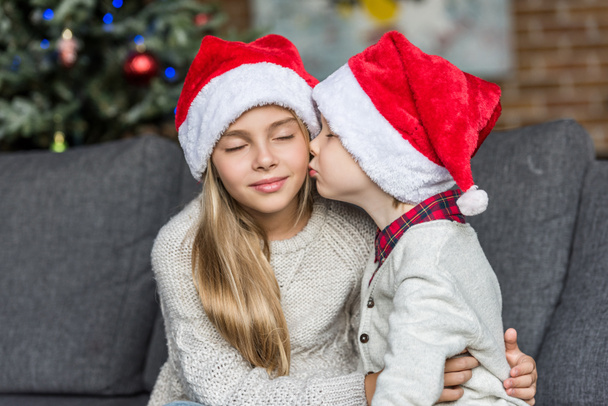 lindo niño en santa hat besos hermana en Navidad
 - Foto, imagen