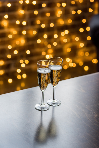 close-up view of two glasses of champagne and golden bokeh background - Zdjęcie, obraz