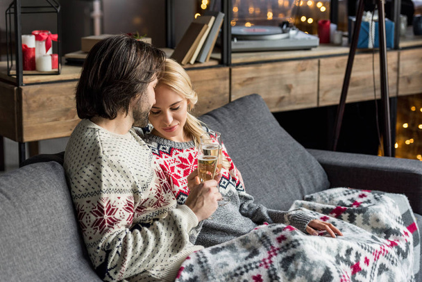 Szczęśliwa Młoda para siedzi razem i pić szampana w okresie Bożego Narodzenia - Zdjęcie, obraz