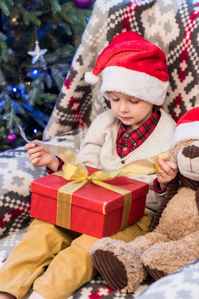 adorable little boy in santa hat opening christmas present  - Foto, Imagem