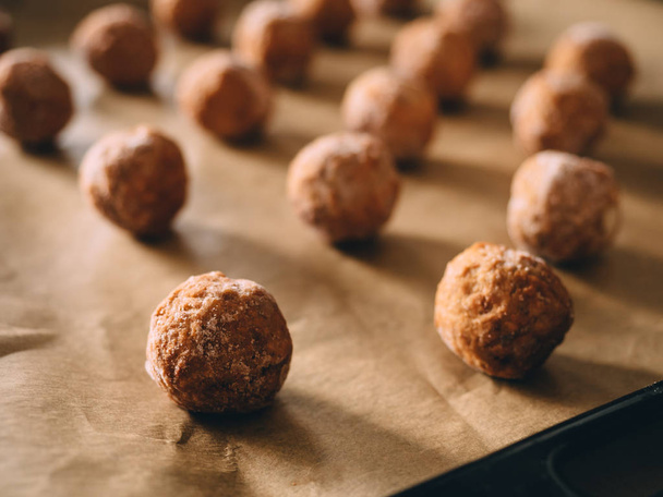 Raw frozen meat balls on baking sheet with paper. - Foto, afbeelding