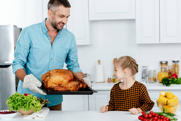 happy father and adorable little daughter baking turkey for thanksgiving dinner - Фото, зображення