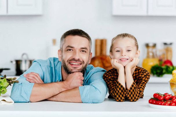 father and adorable little daughter looking at camera on kitchen - Foto, Imagem