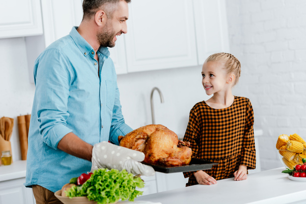father and adorable little daughter baking turkey for thanksgiving dinner - 写真・画像