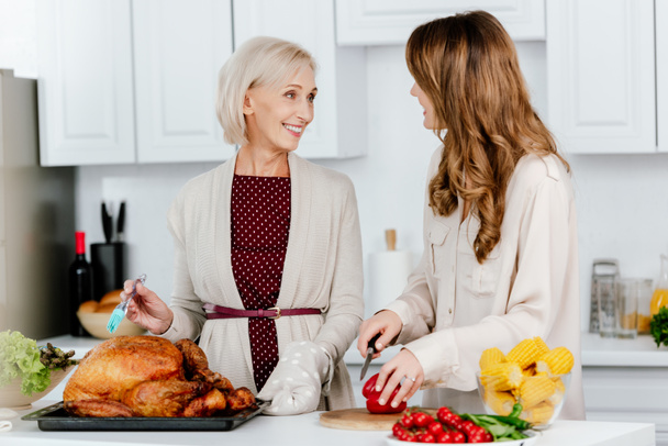 atractiva hija adulta y madre mayor cocinando cena de acción de gracias juntos
 - Foto, imagen