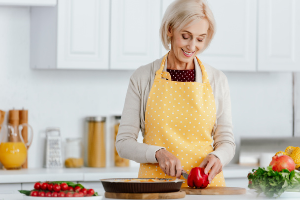 onnellinen vanhempi nainen esiliina ruoanlaitto keittiössä
 - Valokuva, kuva