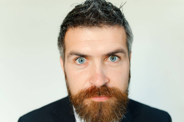 Людина з товстою бородою і блакитними очима ізольована на сірому фоні. Хлопець з імбирною бородою в темному формальному костюмі. Бізнесмен з концентрованим і усміхненим обличчям, крупним планом. Концепція бізнесу та довіри
 - Фото, зображення