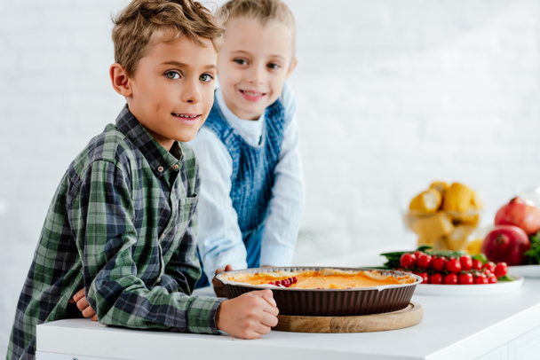 siblings with pumkin pie looking at camera together at kitchen - Фото, зображення
