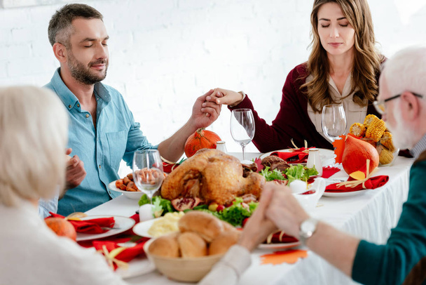 family praying at served table with turkey before thanksgiving celebration  - Foto, Imagem
