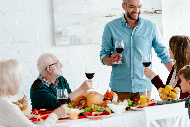 Gelukkig volwassen man met glas wijn maken toast terwijl zijn familie vakantie eten op thanksgiving  - Foto, afbeelding