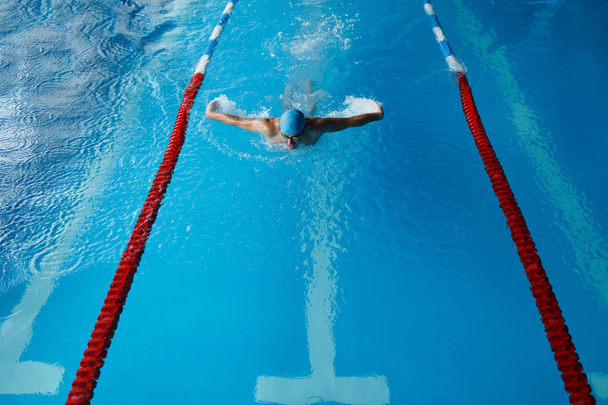 Photo of sports man in blue cap swimming in pool - Foto, Imagen