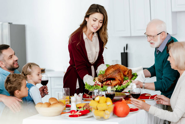 grandfather and adult woman carrying baked turkey for thanksgiving dinner with family  - Фото, зображення