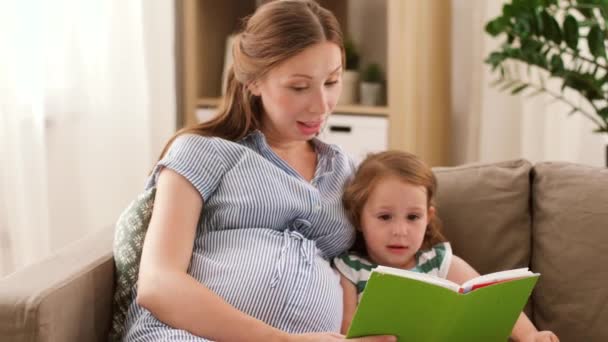 pregnant mother and daughter reading book at home - Video, Çekim