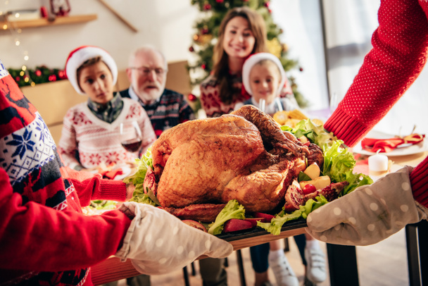 cropped image of people carrying holiday turkey for christmas dinner with family at home - Foto, Imagem