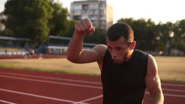 Accelerated footage of a male boxer while training process on the outdoors stadium. Portrait of a man boxing with invisible opponent, punching. Side view - Séquence, vidéo