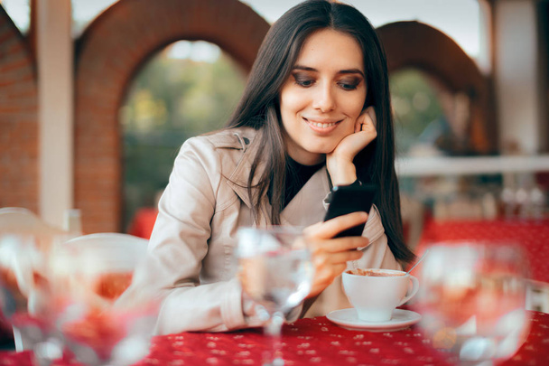 Frau checkt ihr Smartphone in einem Restaurant - Foto, Bild