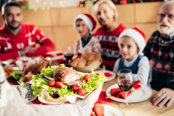 partial view of woman carrying meal for christmas dinner with family at home  - Foto, Bild