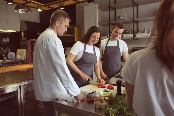 Chef-kok en groep jongeren tijdens kooklessen - Foto, afbeelding